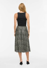 Czarny dopasowany top na ramiączkach połączony z plisowaną, sięgającą połowy długości spódnicą z monochromatycznym wzorem w jodełkę.