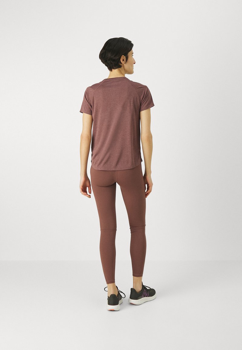 Haut de sport bordeaux et leggings assortis, tous deux en tissu lisse. Le haut a des manches courtes, et les leggings sont ajustés à la longueur des chevilles.