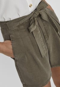 Olive green shorts made of soft fabric, featuring a tie waist and pleated front with side pockets. Smooth texture and tailored design.