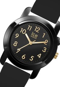 Orologio da polso in silicone nero con quadrante nero, numeri arabi dorati, lancette delle ore e dei minuti dorate, e una piccola corona dorata sul lato.