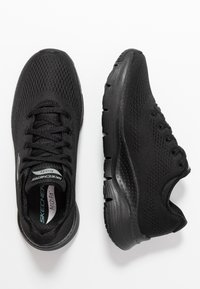 Svarta träningsskor gjorda av ventilerande mesh och syntetiskt material. Har en texturerad sula och vadderad innersula för komfort.