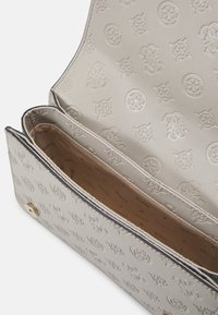 Textureret grå håndtaske med prægede logo mønster, guld hardware og et rummeligt beige interiør med rum til organisering.