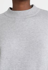 Grauer Strickpullover mit einem gerippten Rundhalsausschnitt. Das Material wirkt weich mit einer subtilen Textur und gleichmäßiger Farbverteilung.