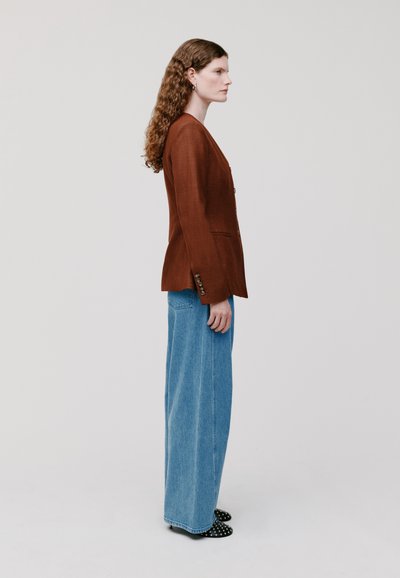 Bruine linnen blazer met een getailleerde pasvorm, éénknops sluiting en twee voorzakken. Gepaard met wijde blauwe denim en polka-dot hakken.