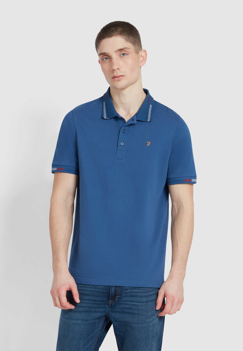 Blauwe poloshirt van katoen, voorzien van een twee-knopen sluiting, gestreepte kraag met rode accenten, en geribde mouwzoom.