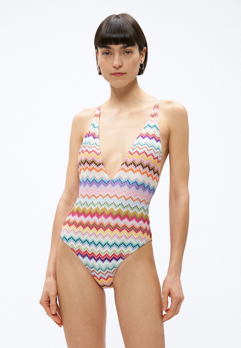 Kolorowy strój kąpielowy jednoczęściowy z wzorem zygzaków, głębokim dekoltem w kształcie litery V, szerokimi ramiączkami i wysokim wycięciem nogawek, wykonany z rozciągliwego materiału.