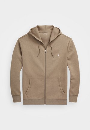 Beige Kapuzenjacke mit Reißverschluss, Vordertaschen, Kordelzug am Kapuzenrand, gerippten Bündchen und kleinem weißem Logo auf der linken Brust.