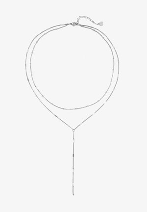 Collier délicat en argent superposé avec deux chaînes fines et une chaîne pendante verticale s'étendant depuis la couche inférieure, équipé d'un petit fermoir en forme de cœur.