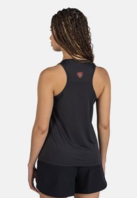 Czarny sportowy top na ramiączkach wykonany z gładkiego materiału, z plecami w stylu racerback, z logo na górnej części pleców, zestawiony z czarnymi szortami.