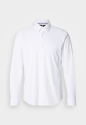 Camisa blanca de manga larga hecha de una tela suave, con cuello de botón y seis botones en el frente; los puños están ajustados para un acabado impecable.