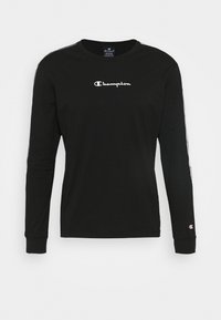 Schwarzes Langarmshirt aus Baumwolle mit einem weißen "Champion"-Logo auf der Brust und kontrastierenden Streifen an den Ärmeln.