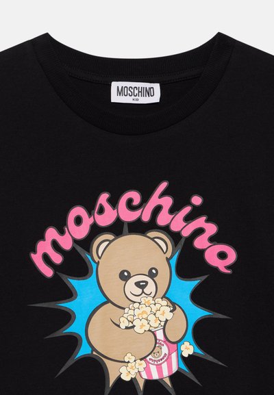 Черна детска тениска Moschino с меченце, държащо пуканки в розова и бяла ивицирана кофичка под розов надпис Moschino.