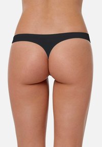 String noir avec un design minimaliste et une texture lisse, présentant une taille fine et une couverture arrière minimale.