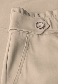 Pantalon en tissu khaki avec une texture lisse, une taille ajustable avec un détail froncé, et une fermeture à bouton argenté.