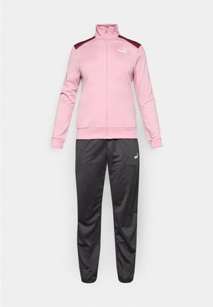 Roosa ja marooni värvi Puma tõmblukuga jakk koos mustade Puma spordipükstega, esitlemisel lihtsal valgel taustal.