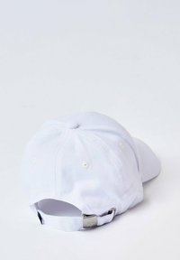 Gorra de béisbol blanca hecha de algodón con un acabado texturizado, que cuenta con ojales cosidos, una correa ajustable y un logotipo en la parte posterior.
