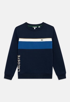 Sweatshirt azul-marinho com riscas horizontais em vários tons de azul e branco. "LACOSTE" impresso em bege claro na lateral.