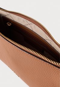 Καφέ δερμάτινο πουγκί με υφή στην εξωτερική επιφάνεια, χρυσό φερμουάρ και μπεζ επένδυση με διακριτική σήμανση. Το εσωτερικό διαθέτει πολλαπλές θήκες.