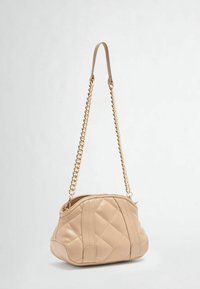 Beige gesteppte Handtasche mit runder Form, ausgestattet mit einem Kettenriemen und einem sichtbaren Reißverschluss. Glatte Oberfläche mit vertikalen Nahtakzenten.