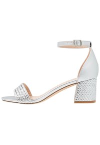 Silver heeled sandal with a woven front strap, flat sole, and an ankle strap featuring a buckle. Smooth and textured materials.
