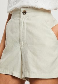 Helle beige Shorts aus strukturiertem Stoff, mit hohem Taillenbund, einem Knopfverschluss vorne und seitlichen Taschen.