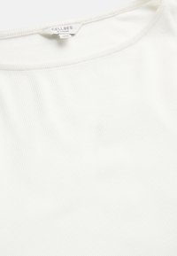 Witte geribbelde T-shirt met een ronde halslijn en een zachte textuur. De stof vertoont fijne horizontale strepen, met het label 'CELLBES OF SWEDEN'.