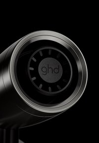 Gros plan sur un appareil cylindrique noir et argent avec un indicateur LED circulaire affichant "gnd" sur un fond sombre.