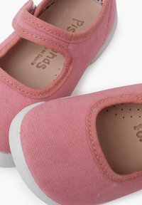 Pink canvas Mary Jane shoes with a white rubber sole. Features a strap across the instep and a breathable lining with small perforations.
