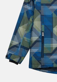 Giacca blu e verde con fantasia geometrica, tasca con zip e polsini neri a contrasto. Realizzata in tessuto liscio.