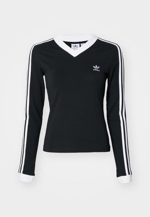 Camisa negra de manga larga con escote en V, cuello blanco y tres rayas blancas en cada manga. Presenta un logo de Adidas en el pecho.