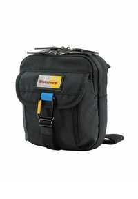 Bolso cruzado de nylon negro con tapa frontal, herrajes plateados, acentos en azul y amarillo, y un parche de marca. Cierre de cremallera en la parte superior.