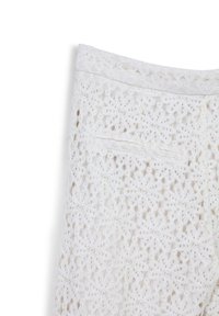 Pantalon en dentelle blanche avec un motif floral, doté d'une taille cousue et d'une poche arrière. La texture est délicate et aérienne.
