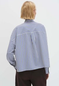 Gestreiftes Langarmshirt in Blau und Weiß mit lockerer Passform, Kragen und Rückenfalte. Aus Baumwolle mit glatter Textur.