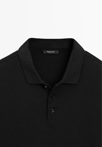 Sort polo skjorte med krave, to knaplukninger og ribbede ærmekanter. Fremstillet af et tekstureret stof. Etiket læser "Massimo Dutti."