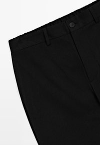Zwarte broek met knoopsluiting, riemlussen en zijzakken op een witte achtergrond.