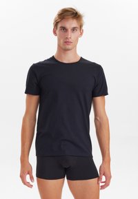 Sort kortærmet crew neck t-shirt lavet af bomuld, med en klassisk pasform og glat tekstur, båret med sorte boxer shorts.