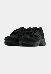 Czarne buty sportowe z siateczkowej i syntetycznej cholewki, masywną podeszwą oraz teksturowanymi akcentami. Posiadają sznurowadła oraz pętelkę z tyłu.
