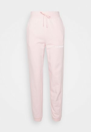 Light pink Calvin Klein sweatpants with elastic waistband, drawstring, cuffed ankles, and white logo on upper left thigh.
