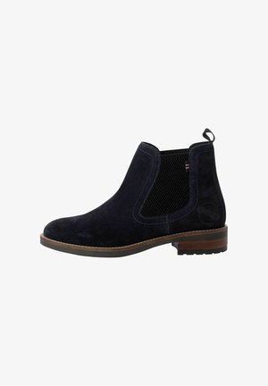 Bottes élégantes en suede marine à la cheville, avec des panneaux latéraux élastiques, des coutures contrastées, une languette de traction et un talon en bois. Surface texturée et forme de bout arrondi.