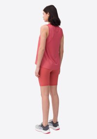 Conjunto de ropa de actividad para mujeres que incluye una camiseta sin mangas, ligera, de color rosa y pantalones cortos rosas, combinados con zapatillas grises y blancas.