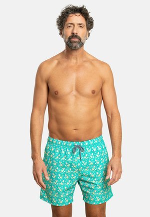 Bañadores en color verde azulado con un estampado de estrellas de mar, cuentan con una cintura con cordón y un tejido ligero de secado rápido. Sin bolsillos visibles.