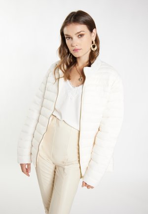 Witte pufferjack met ritssluiting, textuur gequilt ontwerp en staande kraag, gecombineerd met crèmekleurige highwaisted broek en een kanten top.