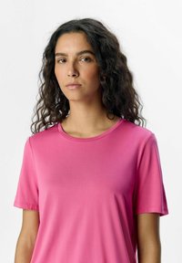 Pink short-sleeve t-shirt with a round neckline, made of smooth fabric, featuring a fitted design and minimal stitching details.