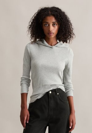 Grijze geribde sweatshirt met een trekkoord en lange mouwen, gecombineerd met zwarte high-waisted jeans, met een relaxed fit en minimale details.