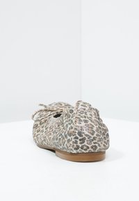 Baleriny w panterkę z miękką tkaniną w górnej części, okrągłym noskiem i małą kokardą. Teksturowana powierzchnia z delikatnym połyskiem. Brązowa podeszwa.