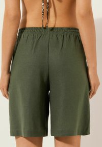 Pantalones cortos verde oliva hechos de una tela suave, con una cinturilla elástica y un corte simple que cae justo por encima de la rodilla.