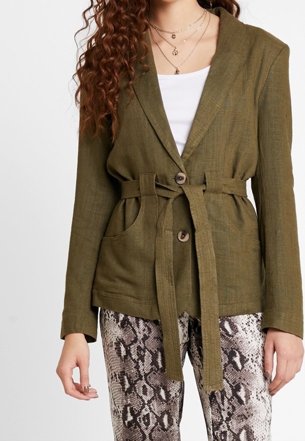 Olivově zelený sako s opaskem vyrobené z texturované tkaniny, se zapínáním na jeden knoflík a dvěma předními kapsami. V páru s kalhotami s hadím potiskem.