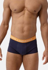 Boxer shorts de color navy con una cinturilla elástica naranja etiquetada "DANISH ENDURANCE". Presenta un diseño ajustado y una textura de tejido suave.