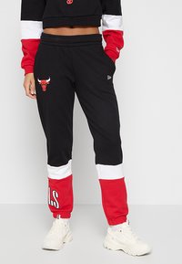 Černé tepláky s červenými a bílými akcenty, na levém stehně s logem Bulls a textem "LS" na dolní části nohavice. Měkká tkanina, elastický pás.