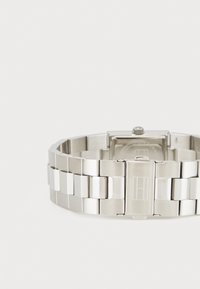 Reloj de acero inoxidable con pulsera de eslabones cepillados y pulidos, caja rectangular y cierre de broche. Presenta un diseño de esfera minimalista.